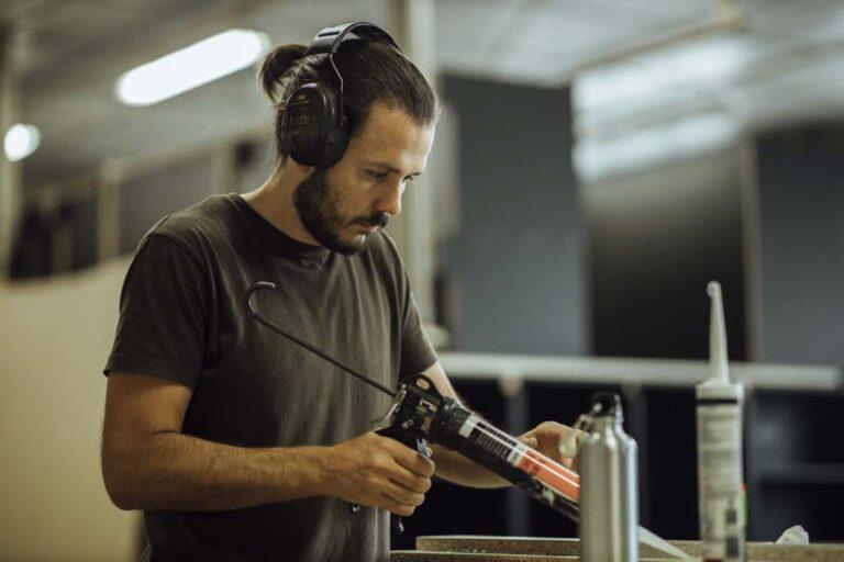 Un homme applique de la colle à l'aide d'un pistolet à colle