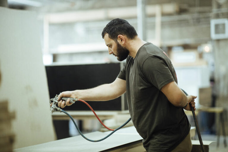 Un homme utilise un spray sur du bois