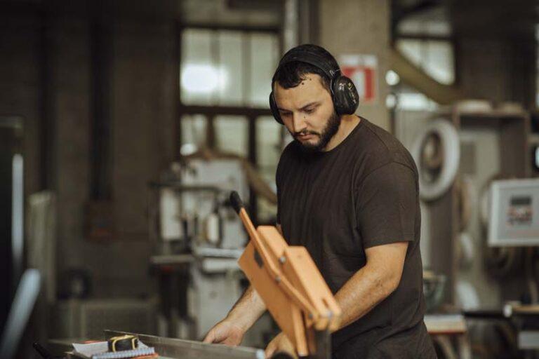 Une homme portant un casque anti-bruit utilise une machine de l'atelier
